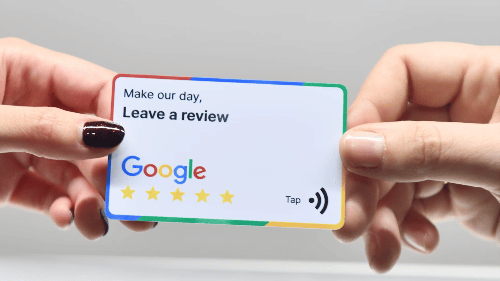 Manos sosteniendo una tarjeta NFC de Google Reviews con el mensaje 'Make our day, Leave a review' y el logo de Google con estrellas