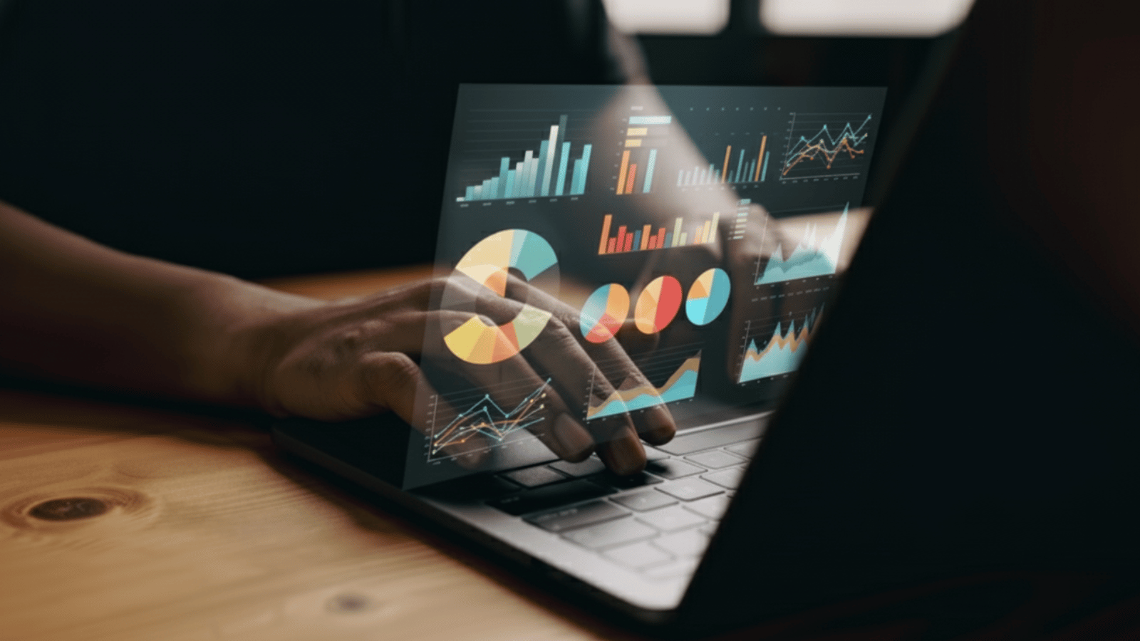 Manos usando una computadora portátil con gráficos y paneles de análisis de datos